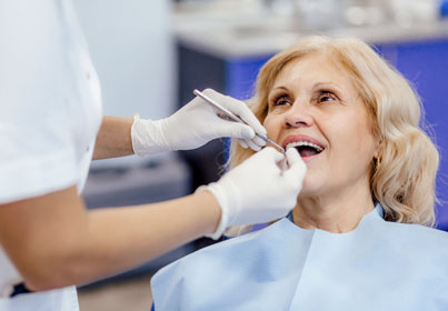 Dentist examining patient's teeth in clinical dental office setting with dental tools.