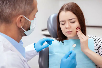 Dentist in blue gloves examining patient's teeth during dental checkup in clinic.