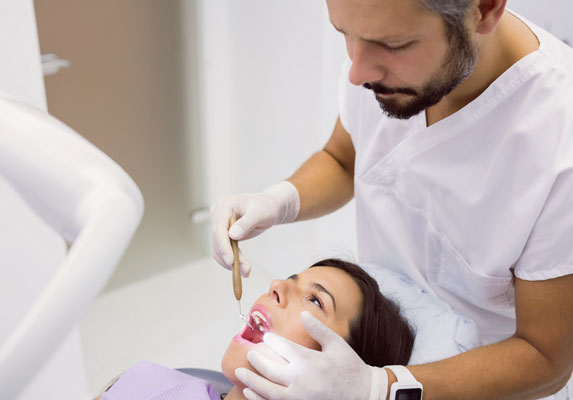 Dentist examining patient's teeth in bright clinical dental office setting.