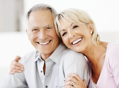 Smiling older couple embracing indoors, representing dental care and healthy lifestyle for seniors.