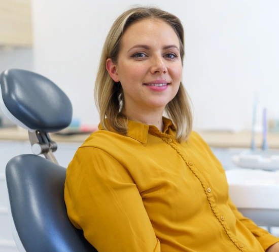 Woman in yellow shirt smiling in dental office chair